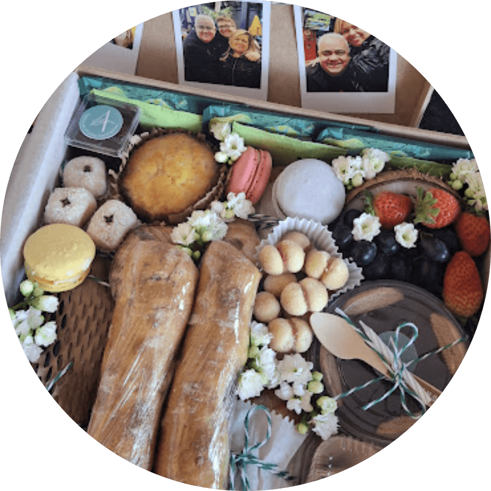 detalhe de cesta de café da manhã ou gift box composta com pães, torradas, tortinha, macarons, café, chá, frutas. 