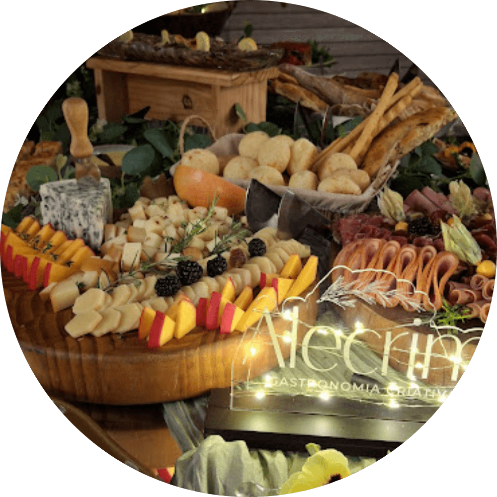 mesa gastronômica para eventos intimistas, contendo charcutaria, queijos, pães, nuts, mini sanduíches, frutas e iguarias artesanais.